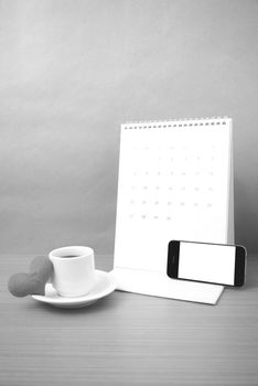 coffee,phone,calendar and heart on wood table background black and white color