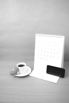 coffee,phone,calendar and heart on wood table background black and white color