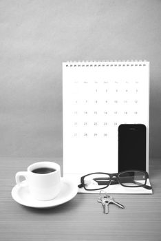 coffee,phone,eyeglasses,calendar and key on wood table background black and white color