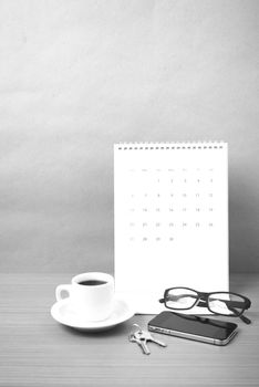 coffee,phone,eyeglasses,calendar and key on wood table background black and white color