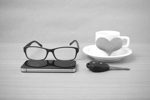 coffee,phone,eyeglasses and car key on wood table background black and white color