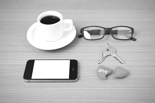 coffee,phone,eyeglasses and key on wood table background black and white color