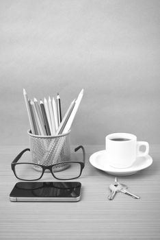 coffee,phone,eyeglasses,color pencil and key on wood table background black and white color