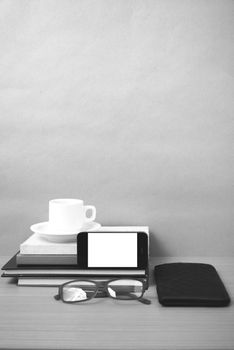 coffee,phone,eyeglasses,stack of book and wallet on wood table background black and white color