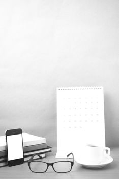 coffee,phone,eyeglasses,stack of book and calendar on wood table background black and white color