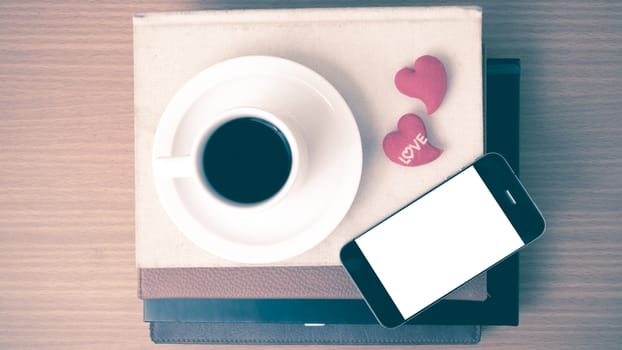 coffee,phone,stack of book and heart on wood table background vintage style