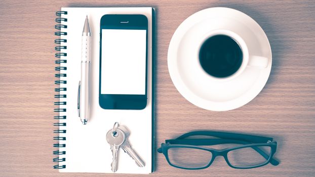 coffee,phone,notepad,eyeglasses and key on wood table background vintage style