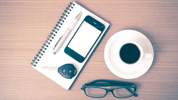 coffee,phone,notepad,eyeglasses and car key on wood table background vintage style