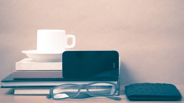 coffee,phone,eyeglasses,stack of book and wallet on wood table background vintage style