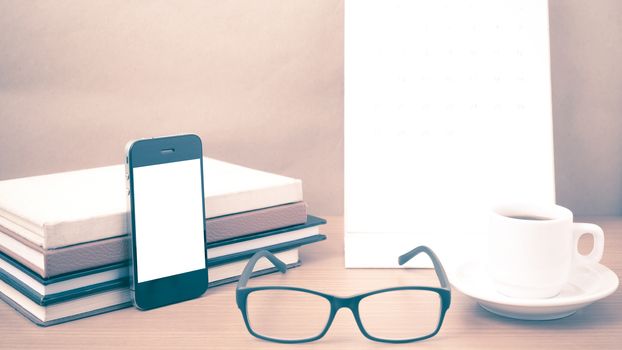 coffee,phone,eyeglasses,stack of book and calendar on wood table background vintage style