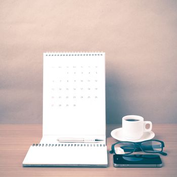 coffee,phone,eyeglasses,notepad and canlendar on wood table background vintage style