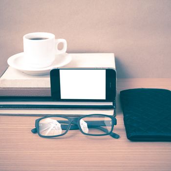 coffee,phone,eyeglasses,stack of book and wallet on wood table background vintage style