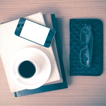 coffee,phone,eyeglasses,stack of book and wallet on wood table background vintage style