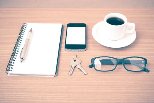 coffee,phone,notepad,eyeglasses and key on wood table background vintage style