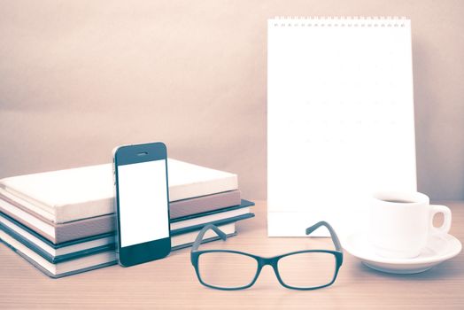 coffee,phone,eyeglasses,stack of book and calendar on wood table background vintage style