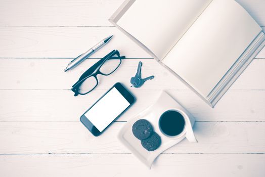 coffee cup with cookie,phone,open notebook and eyeglasses on white wood table vintage style