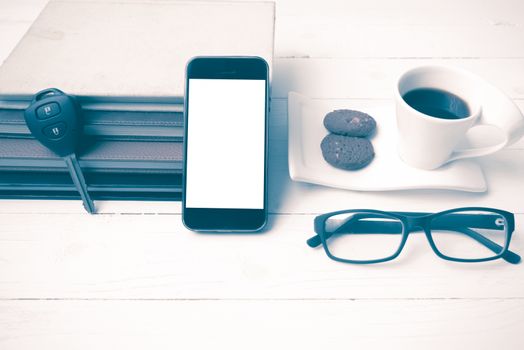 coffee cup with cookie,phone,stack of book and car key on white wood table vintage style