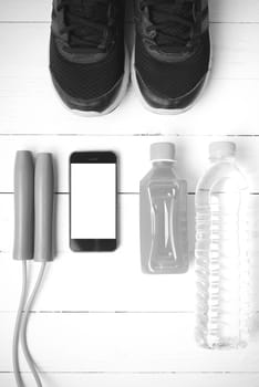 fitness equipment : running shoes,jumping rope,water,juice and phone on white wood background black and white color