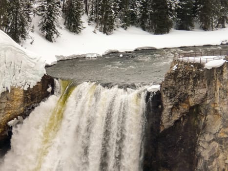 View at Yellowstone Fall on Yellowstone River with snow in forest and on viewpoint.