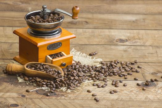  coffee grinder on wooden background with roasted coffee beans