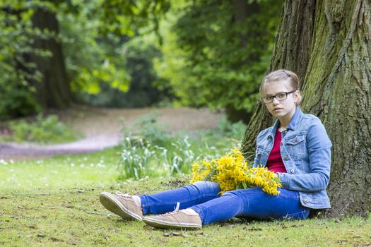 girl with big bouquet of spring flowers sitting in the park