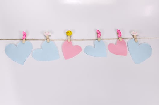 Beautiful paper hearts connected with a rope on white paper background.