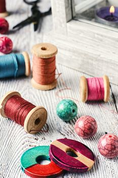 Beads and spools of thread for needlework on bright background