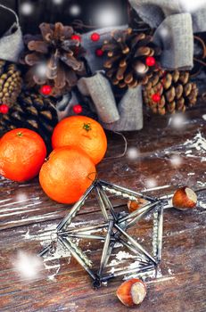 Woven Christmas wreath decorated with cones on background of ripe tangerines
