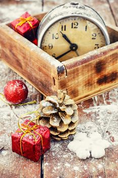 Stylish wooden box with clock on the background of pine cones and Christmas decorations
