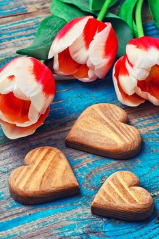 light bouquet of red tulips and  wooden heart symbolic