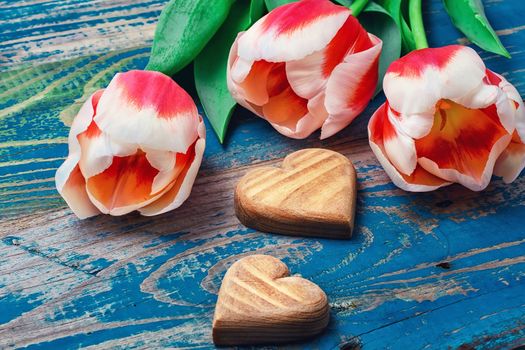 light bouquet of red tulips and  wooden heart symbolic