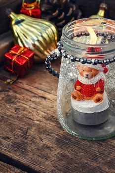 Burning Christmas candle in the shape of a bear cub in glass stylish candle holder