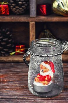 Burning Christmas candle in the shape of a bear cub in glass stylish candle holder