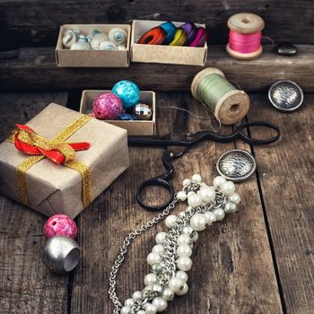 Old scissors,spools of thread,buttons and beads on wooden table