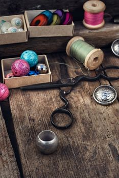 Old scissors,spools of thread,buttons and beads on wooden table