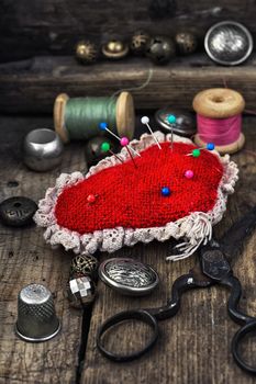 Scissors,thread,buttons and needles on wooden vintage background.