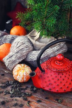 Cast iron kettle red,tangerine,tea leaves on wooden background