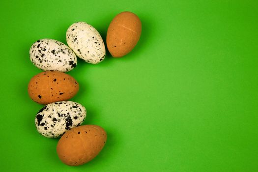 Six chicken eggs, speckled and white smooth isolated on a light green background with free space for text on the right side.Close, horizontal view.