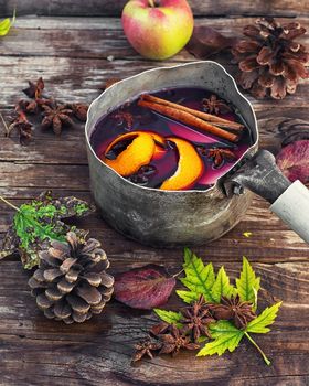 sangria in an old-fashioned bowler hat on background strewn with autumn leaves and cones.