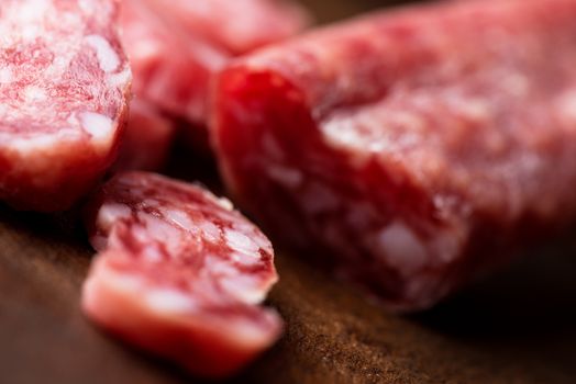 Spanish salami on wooden background close up with shallow DOF.