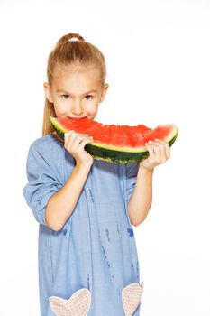 Cute girl in a blue dress eating red juicy watermelon