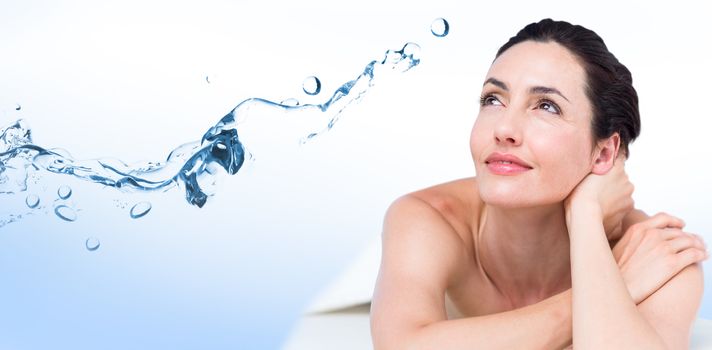 Smiling brunette relaxing on massage table against water bubbling on white surface