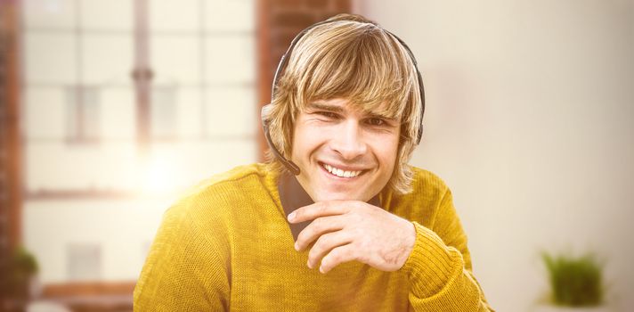 Smiling hipster businessman using headset against laptop on desk with glasses and notepad