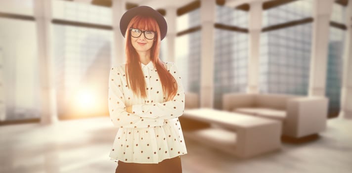 Portrait of a smiling hipster woman with arms crossed against modern room overlooking city