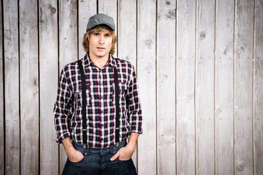 Serious blond hipster staring at camera against wooden planks