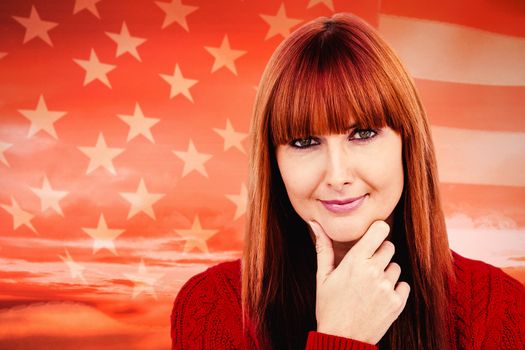 Thoughtful hipster woman looking at camera against american flag rippling against sunrise over mountains