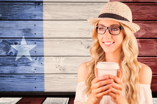 Gorgeous smiling blonde hipster holding take-away cup against composite image of usa national flag