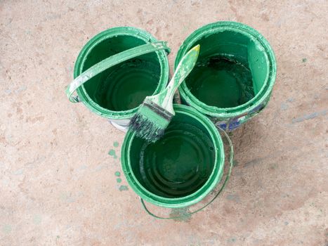 Old paint brush rest on top of green paint Bucket