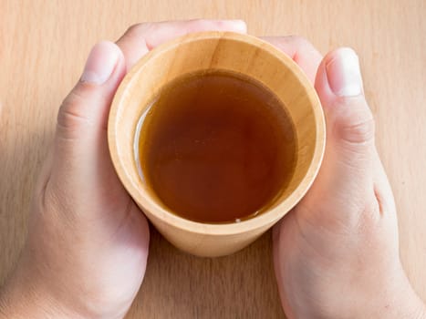 Closeup of female hands holding wood cup of Organic Jasmine Tea