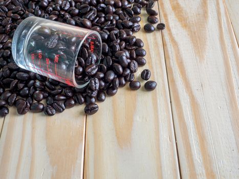 Coffee beans  and a measuring cup on wooden board